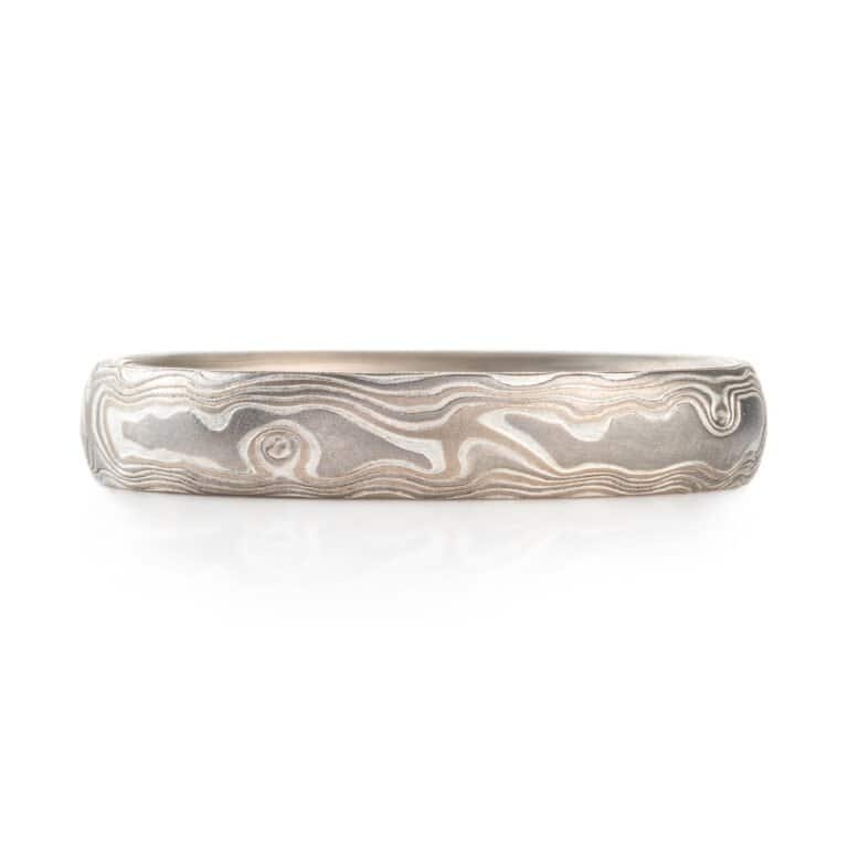 A Mokume Gane band with Woodgrain Pattern and Smoke palette, etched finish, low dome profile, featuring Palladium, 14k white gold, and sterling silver.