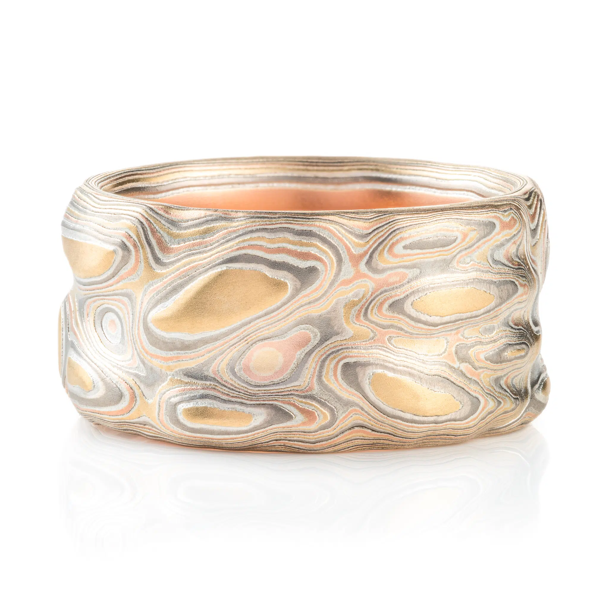 wide man ring in mokume of yellow gold, red gold, silver, and palladium with a recessed blue sapphire. handmade and heirloom quality