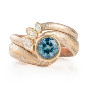 Unique and elegant mokume ring set, featuring contoured band with diamonds and bypass ring with sapphire.