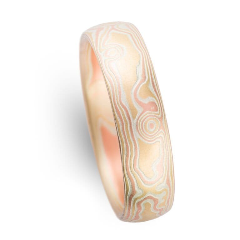 Woodgrain patterned mokume gane ring, plain band with a low dome profile and etched finish, and the ring is made of layers of red gold, yellow gold and silver.