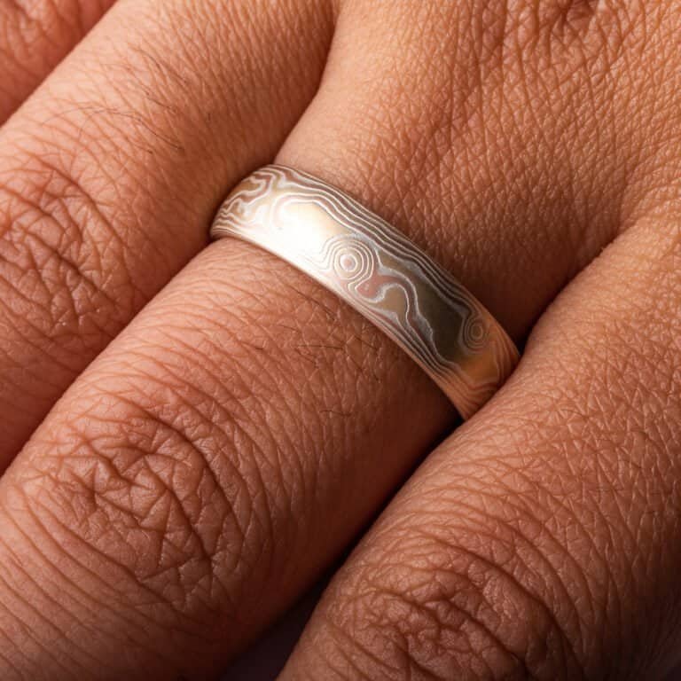 Woodgrain patterned mokume gane ring, plain band with a low dome profile and etched finish, and the ring is made of layers of red gold, yellow gold and silver.