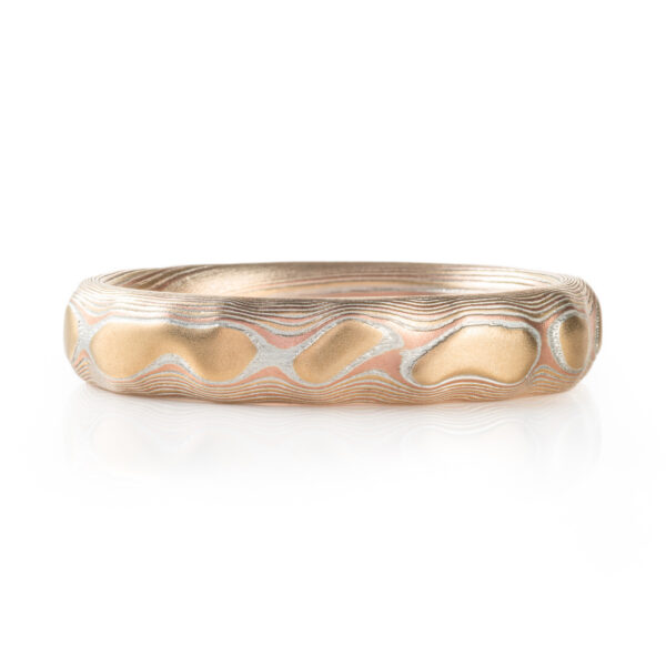 red gold, yellow gold and silver carved mokume ring. hand forged and hand carved. looks like gold islands floating above silver and red lines like a river of metal