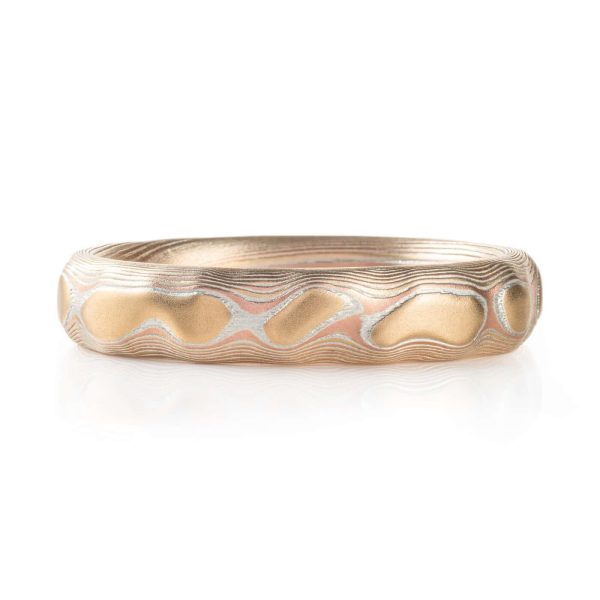 red gold, yellow gold and silver carved mokume ring. hand forged and hand carved. looks like gold islands floating above silver and red lines like a river of metal