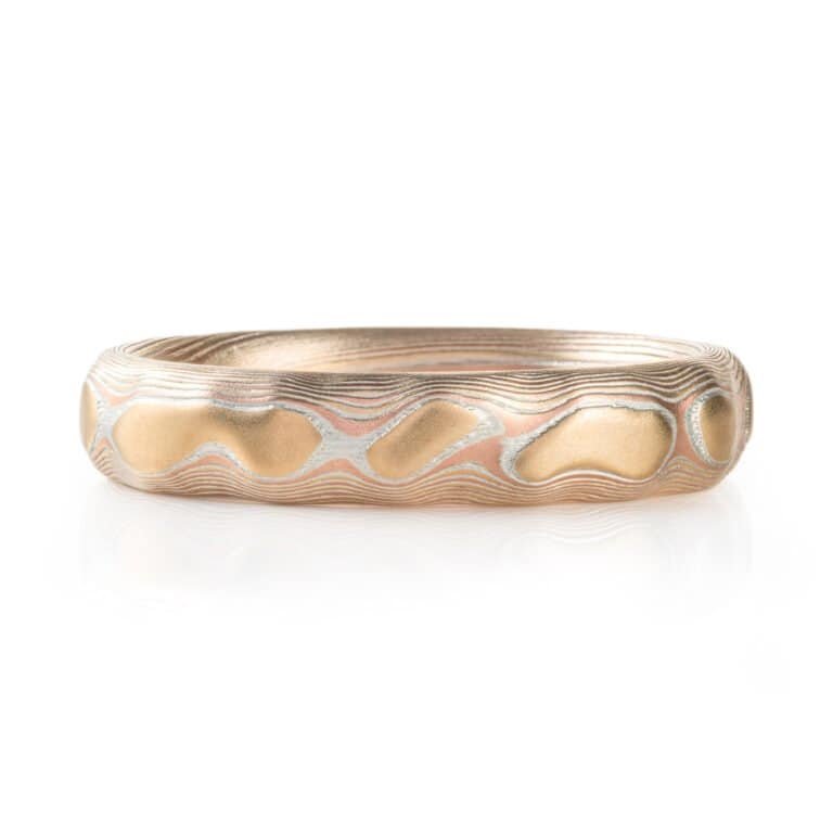 red gold, yellow gold and silver carved mokume ring. hand forged and hand carved. looks like gold islands floating above silver and red lines like a river of metal