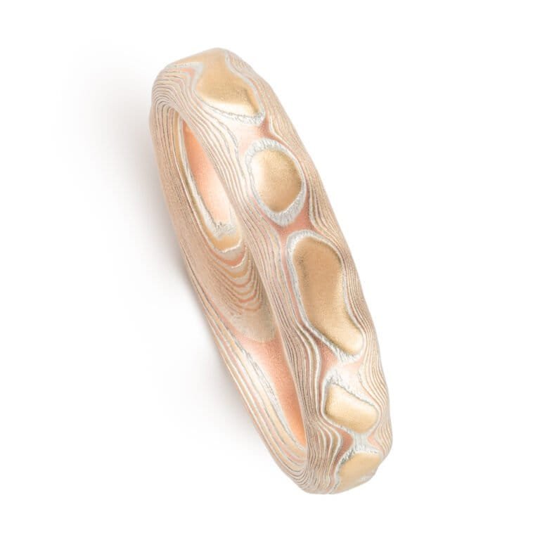 red gold, yellow gold and silver carved mokume ring. hand forged and hand carved. looks like gold islands floating above silver and red lines like a river of metal