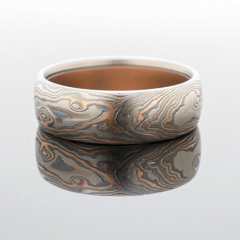 Mokume gane ring in woodgrain pattern and red gold palladium and oxidized silver
