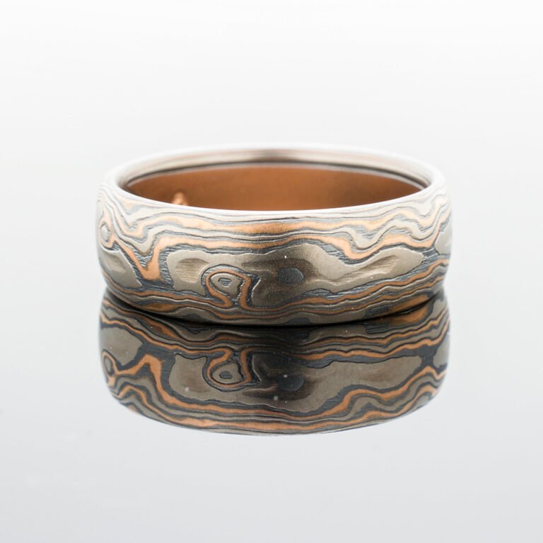 Mokume gane ring in woodgrain pattern and red gold palladium and oxidized silver