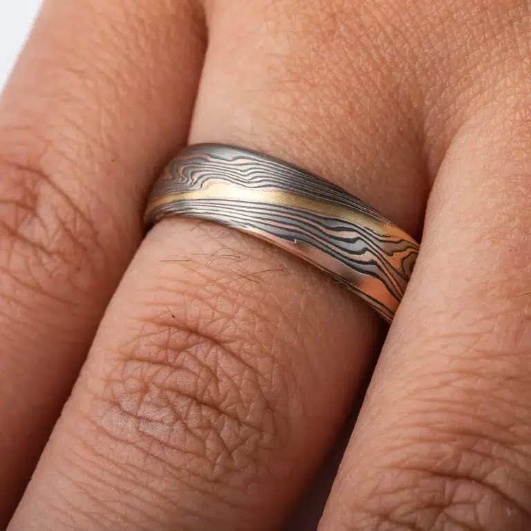 twisted mokume gane band patterned with an added gold stratum for contrast, main palette of the ring is red gold, palladium and oxidized silver