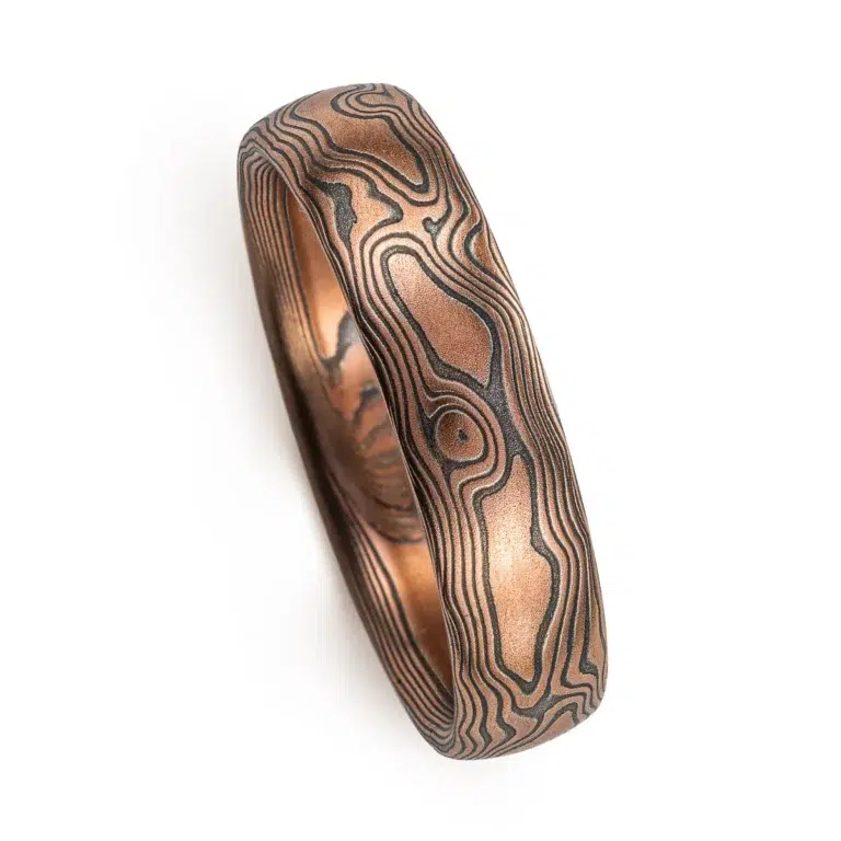 Red gold mokume gane ring with oxidized silver in a woodgrain pattern