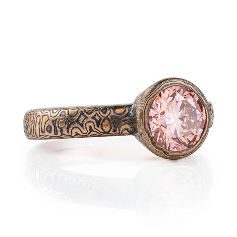 pink diamond mokume gane ring, with patterned bezel to match band, pink stone with red gold yellow gold and oxidized silver