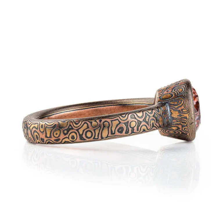 pink diamond mokume gane ring, with patterned bezel to match band, pink stone with red gold yellow gold and oxidized silver