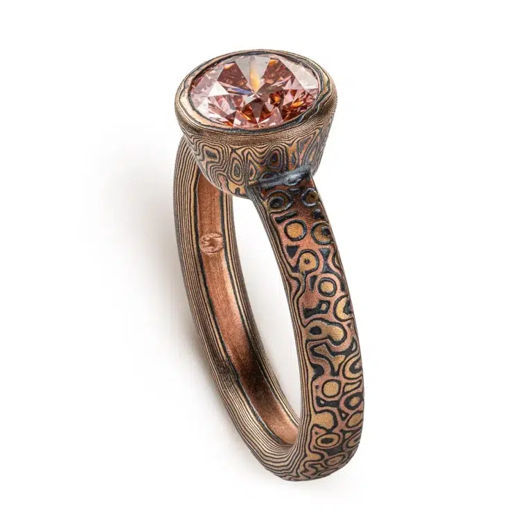 pink diamond mokume gane ring, with patterned bezel to match band, pink stone with red gold yellow gold and oxidized silver