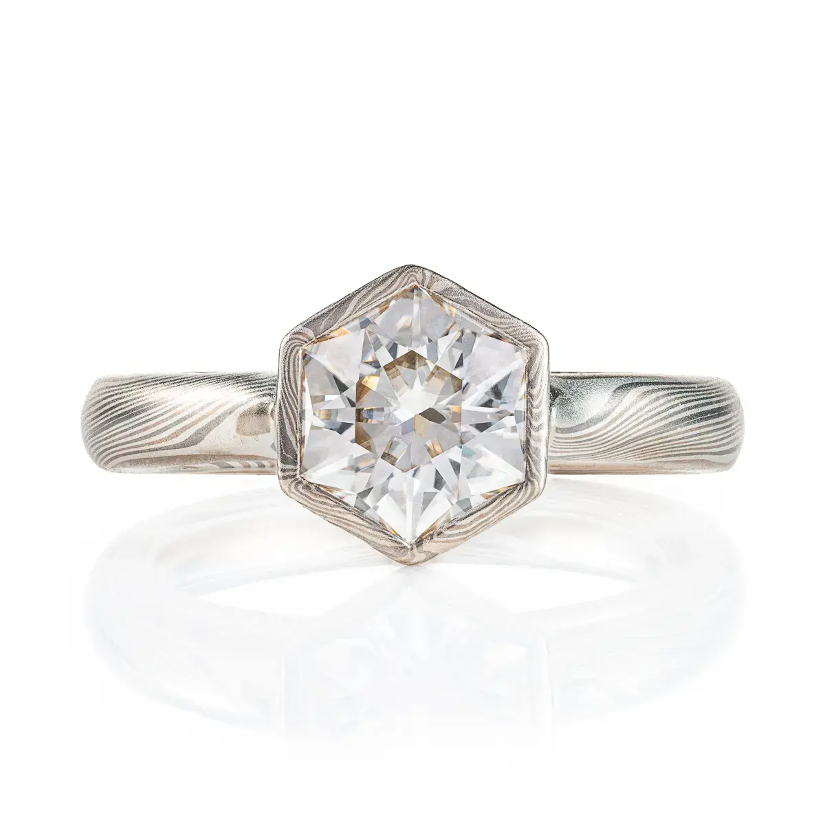 beautiful mokume gane ring with hexagon shaped moissanite in a floating mokume bezel with a light silvery palette