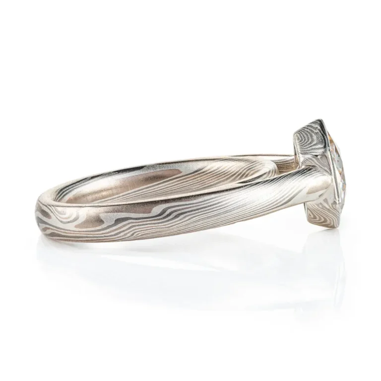 beautiful mokume gane ring with hexagon shaped moissanite in a floating mokume bezel with a light silvery palette