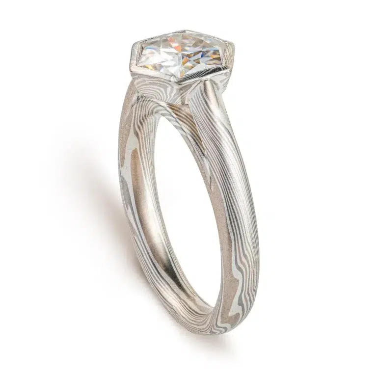 beautiful mokume gane ring with hexagon shaped moissanite in a floating mokume bezel with a light silvery palette