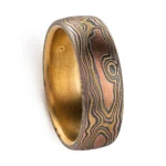 18kt yellow gold mokume gane ring in woodgrain pattern with domed profile, ring is made with golds and oxidized silver