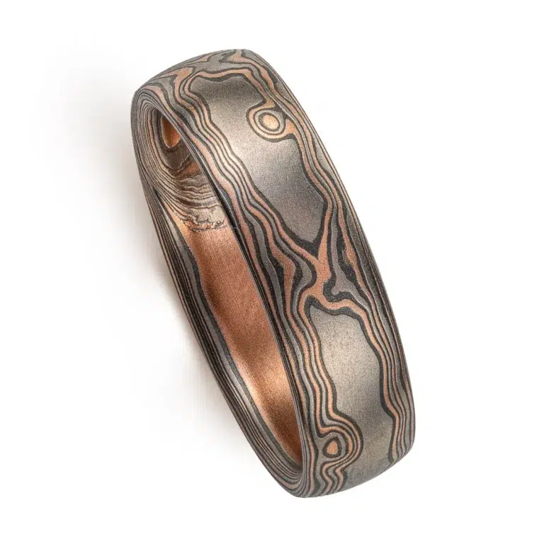 dark rustic feeling mokume gane ring in woodgrain pattern, with red gold, palladium and oxidized silver