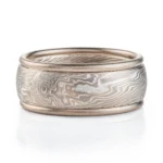 mokume gane twisted pattern ring made of layers of metal in different shades of gray, the ring also has added rails running around the top and bottom edges