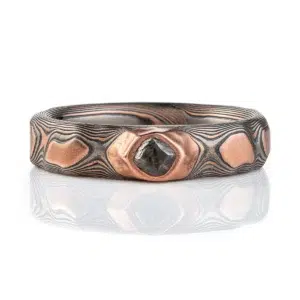 dimensional mokume gane patterned ring made to resemble rocks, with a dark diamond crystal set into it
