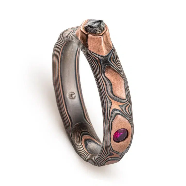 dimensional mokume gane patterned ring made to resemble rocks, with a dark diamond crystal set into it