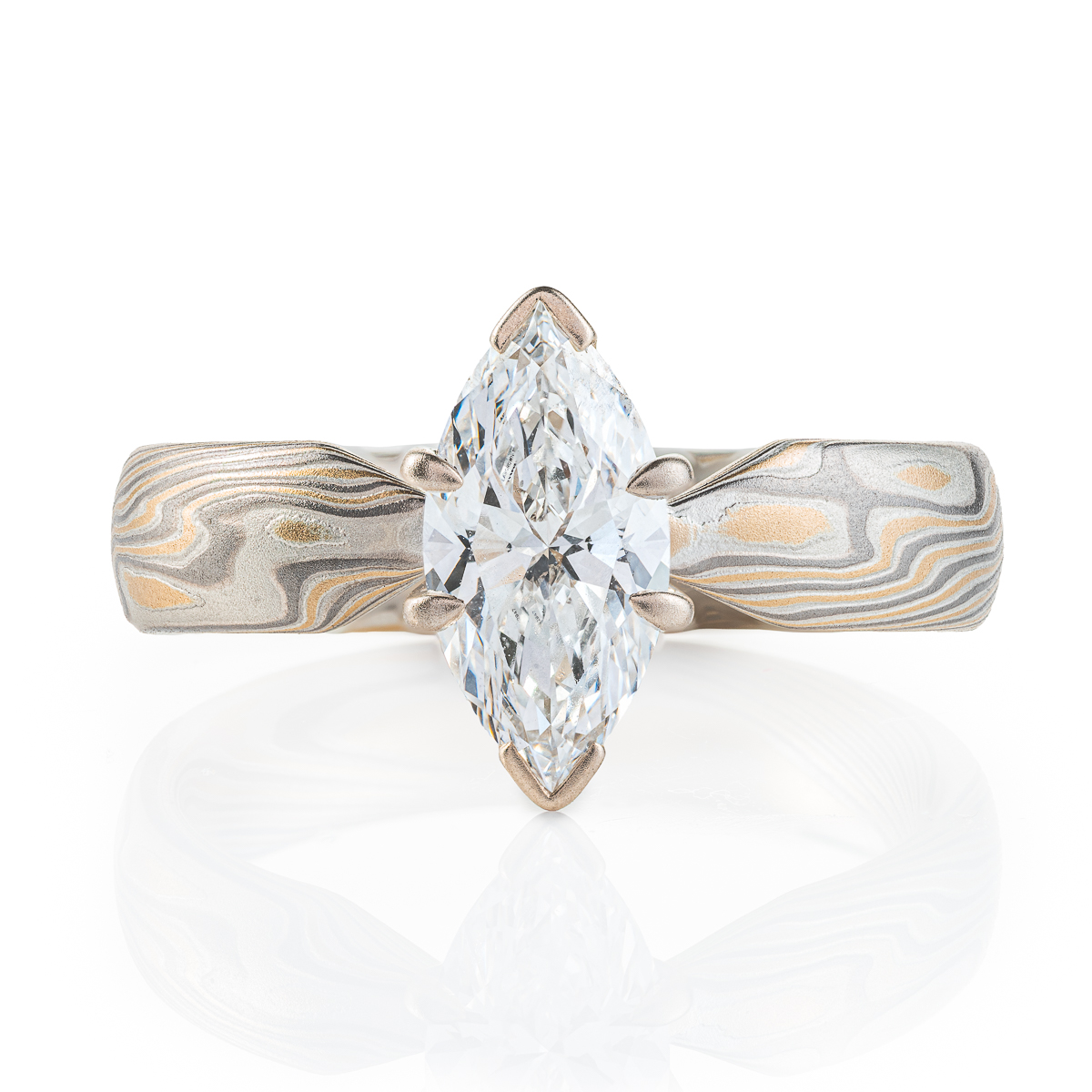 ring with a solitaire stone set in prongs, featuring marquise shaped white stone, band portion is made with yellow gold, palladium and sterling silver