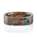 flat band made in soft square shape and rounded interior, made in mokume gane twist style pattern, with flush set small green stone