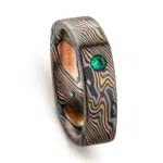 flat band made in soft square shape and rounded interior, made in mokume gane twist style pattern, with flush set small green stone