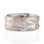 mokume gane patterned ring made to resemble rocky terrain, with a vein of red gold running through the ring in contrast to the silver