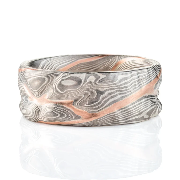 mokume gane patterned ring made to resemble rocky terrain, with a vein of red gold running through the ring in contrast to the silver