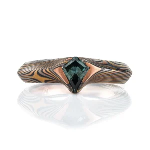 engagement style ring with beveled profile and a kite shaped stone with the point of the stone extending past the edge of the band