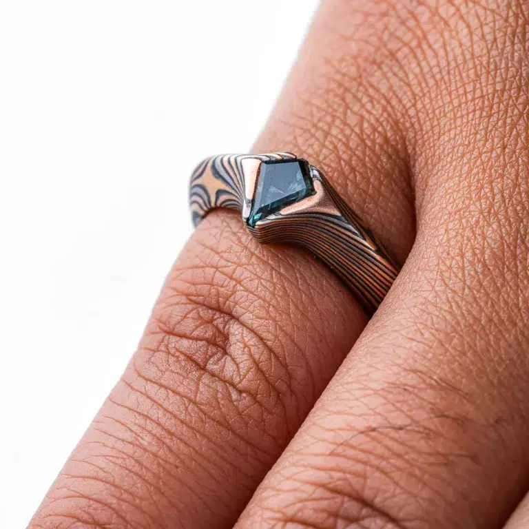 engagement style ring with beveled profile and a kite shaped stone with the point of the stone extending past the edge of the band