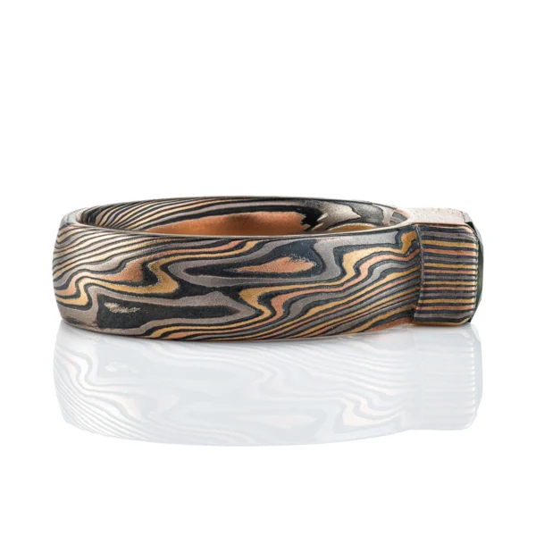 mokume gane ring with multicolored layers of metals, with a large dark green stone set into it