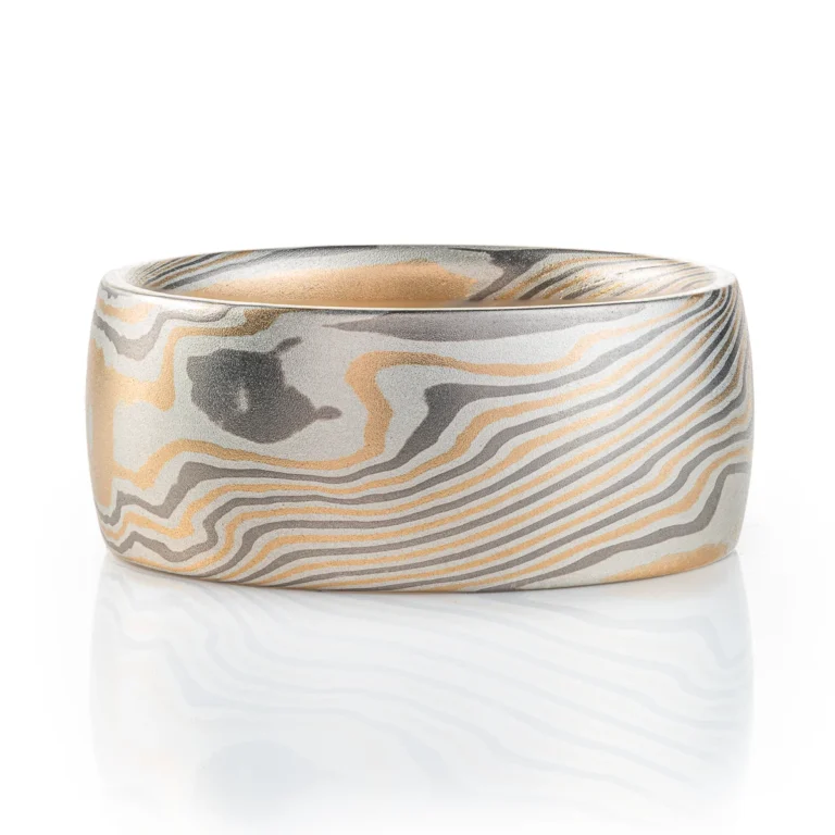 extra wide mokume gane band made in twisted pattern and a combination of yellow gold, palladium and silver, with a low domed profile and smooth finish