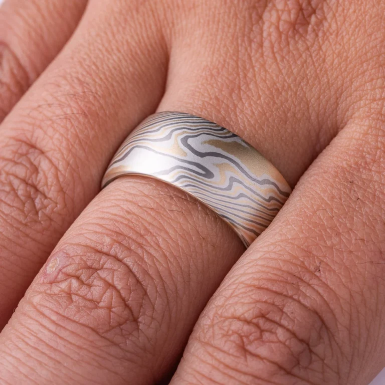 extra wide mokume gane band made in twisted pattern and a combination of yellow gold, palladium and silver, with a low domed profile and smooth finish