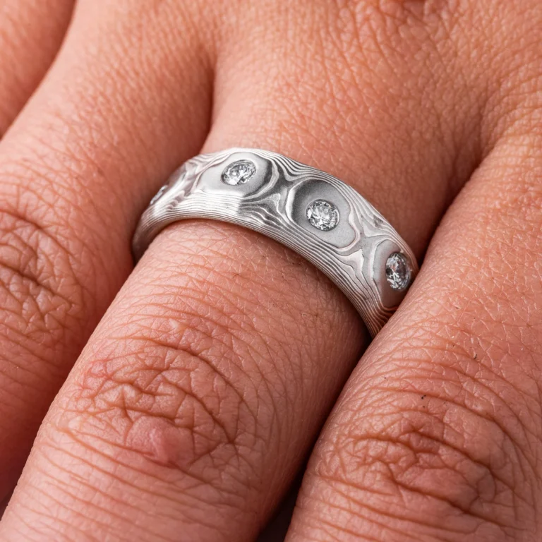 Wide men's style mokume gane band with flush set diamonds scattered around the entire ring for added sparkle. Ring is made in silver and palladium with a textured pattern resembling topography.