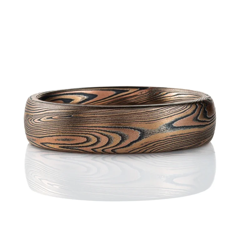 Domed mokume gane band made with linear style patttern, long lines swooping and curling, made with layers of gold and silver.
