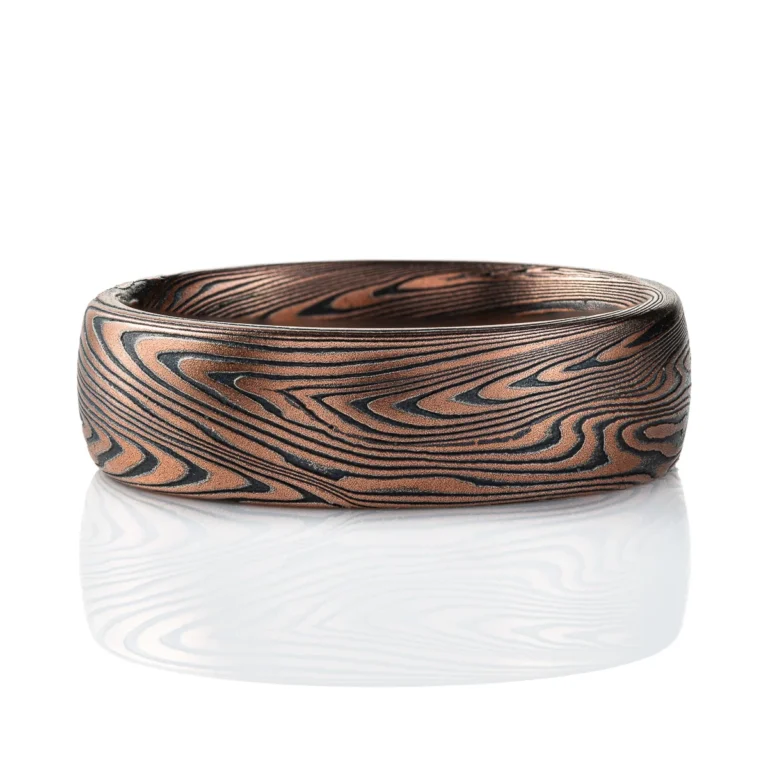 Domed mokume gane band made with linear style patttern, long lines swooping and curling, made with layers of gold and silver.