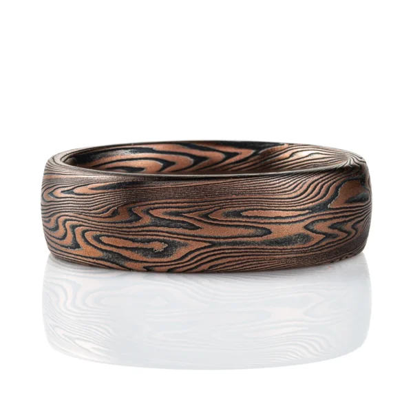 Domed mokume gane band made with linear style patttern, long lines swooping and curling, made with layers of gold and silver.