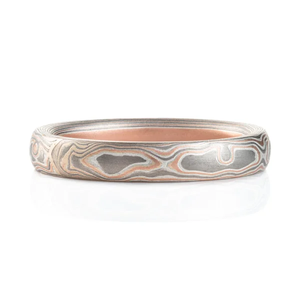 Light feeling narrow wedding band, made in a mokume woodgrain pattern with layers of red gold, palladium and silver, with a slight texture from an etched finish.