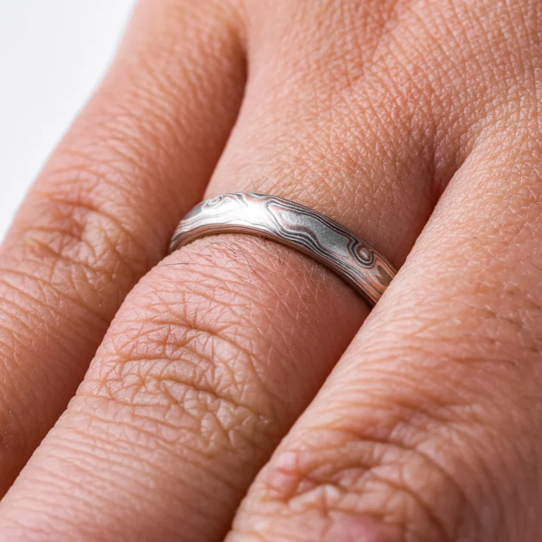 Light feeling narrow wedding band, made in a mokume woodgrain pattern with layers of red gold, palladium and silver, with a slight texture from an etched finish.