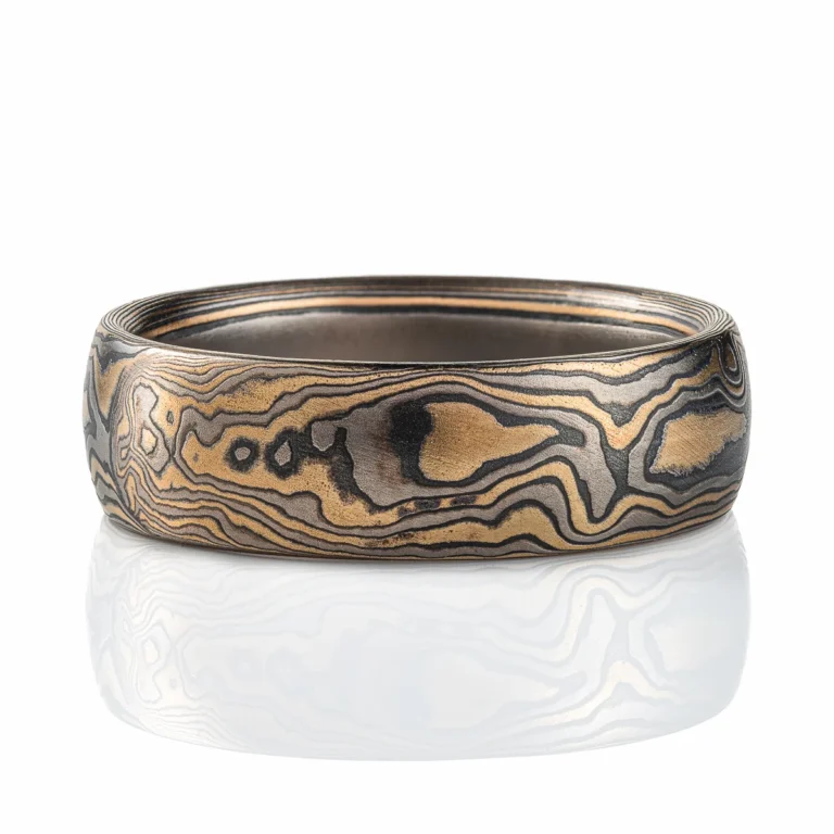 Gold and black mokume gane ring made in classic woodgrain pattern, metal colors used in the ring are yellow gold, palladium and oxidized silver (black in color). The ring has a low dome profile shape and slight texture from an etched finish.