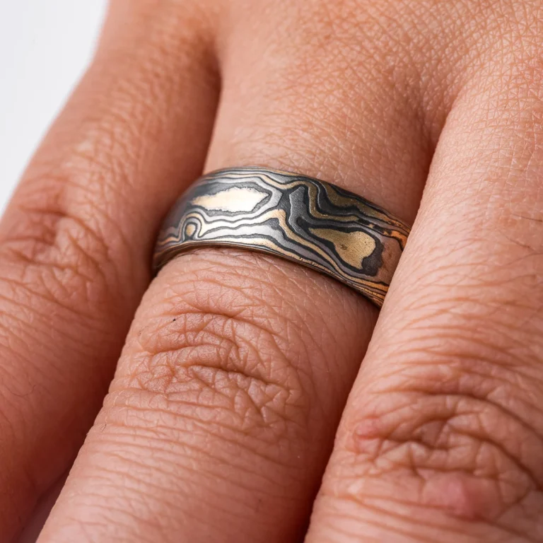 Gold and black mokume gane ring made in classic woodgrain pattern, metal colors used in the ring are yellow gold, palladium and oxidized silver (black in color). The ring has a low dome profile shape and slight texture from an etched finish.