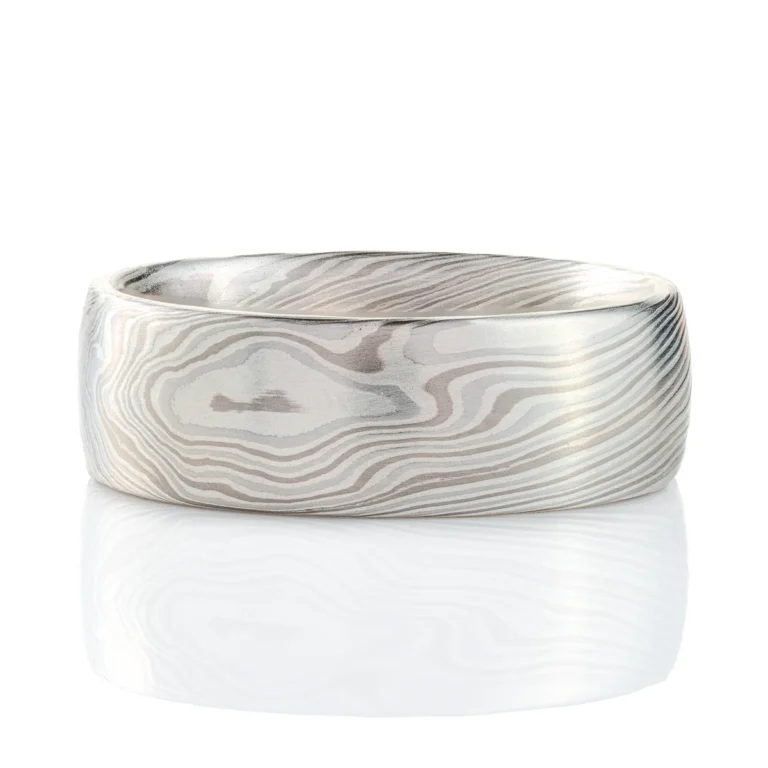 mokume gane band in silvery palette with different shades of gray, made in a twisting pattern and a smooth finish.