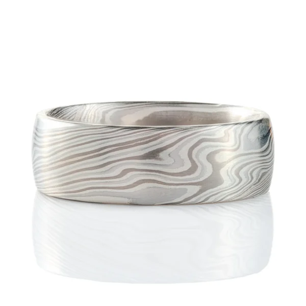 mokume gane band in silvery palette with different shades of gray, made in a twisting pattern and a smooth finish.