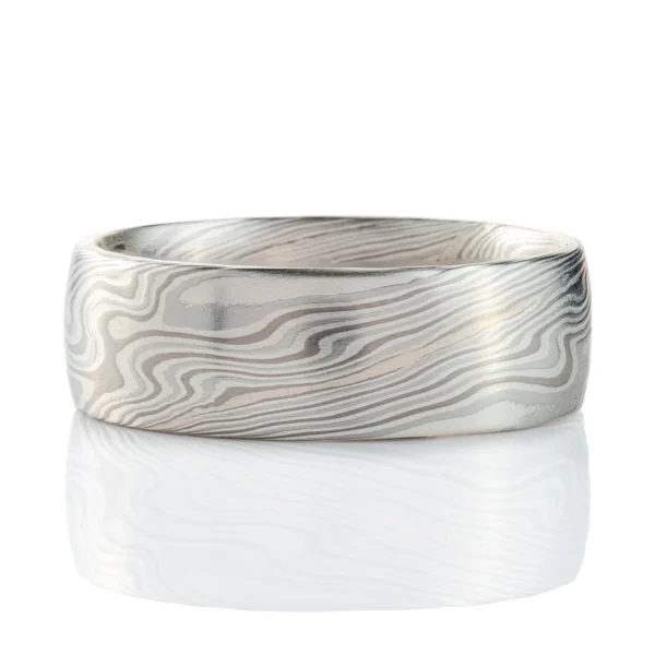 mokume gane band in silvery palette with different shades of gray, made in a twisting pattern and a smooth finish.