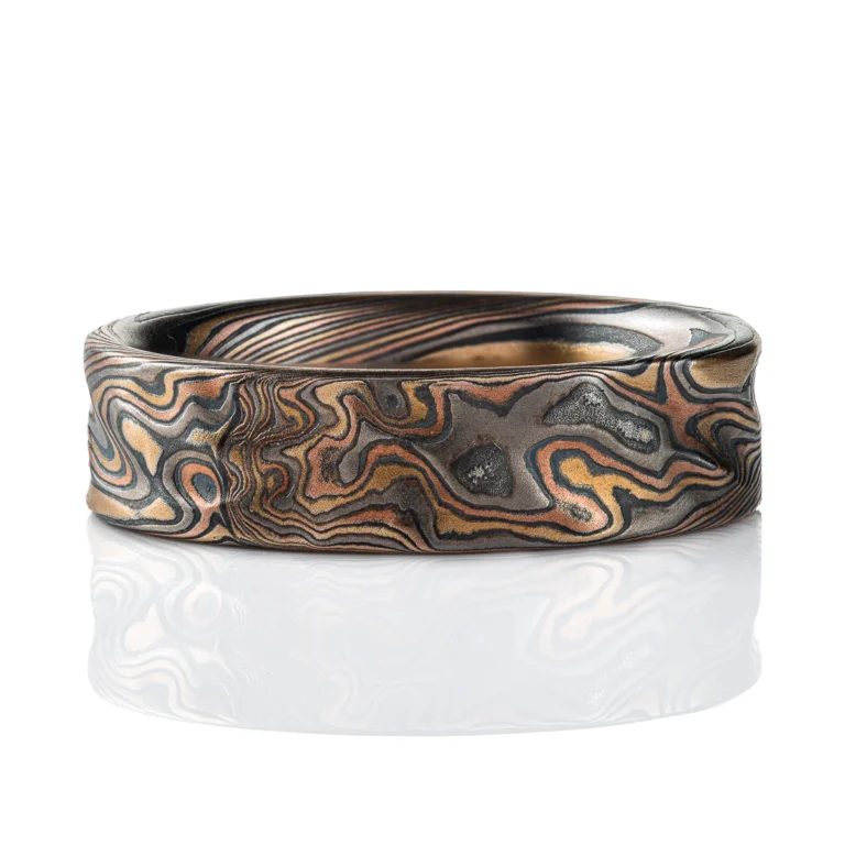 Twisting mokume gane pattern ring in multicolor palette with surface texture.