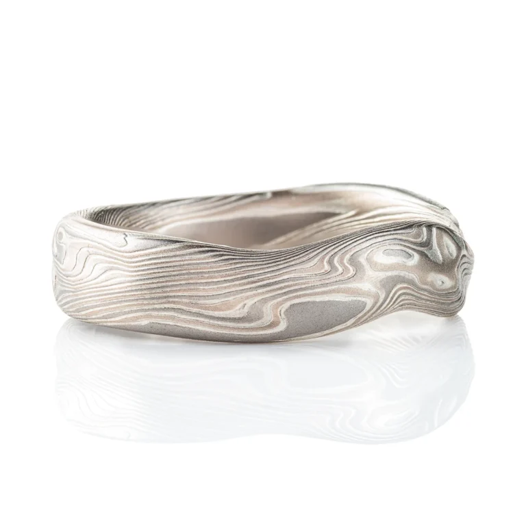 Flat profile band made in mokume twist style pattern, with added surface carving and etched finish for a bumpy texture.