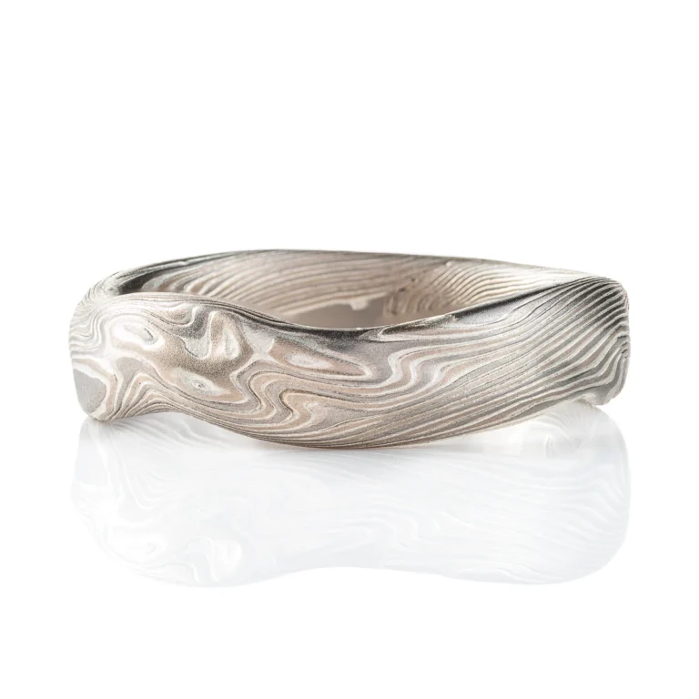 Flat profile band made in mokume twist style pattern, with added surface carving and etched finish for a bumpy texture.