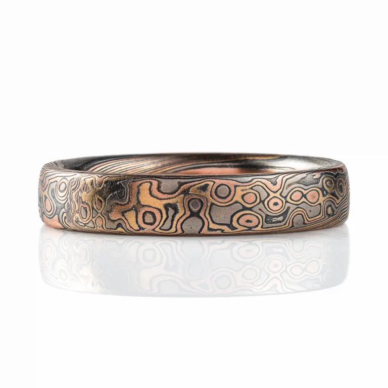 Rustic feeling mokume gane band, narrow width, dark warm toned colors in a swirling mixed pattern.