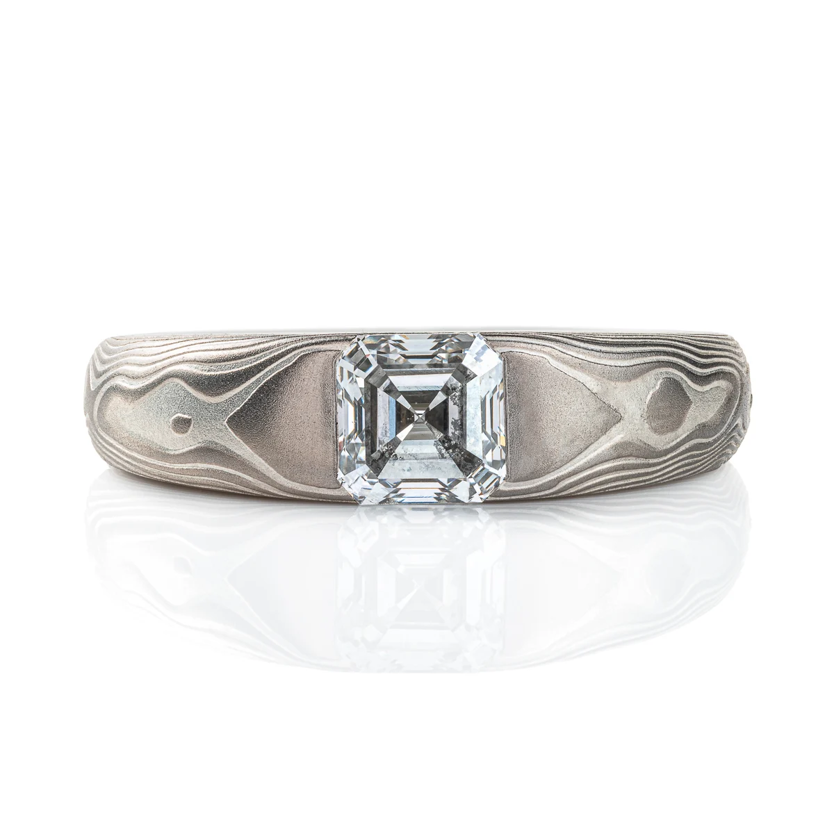 Cathedral style ring with a single diamond set into it, the stone is a soft square shape, the band is light gray and silver in color and tapers towards the underside of the ring.